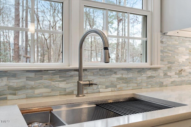 details featuring white cabinetry, sink, and backsplash