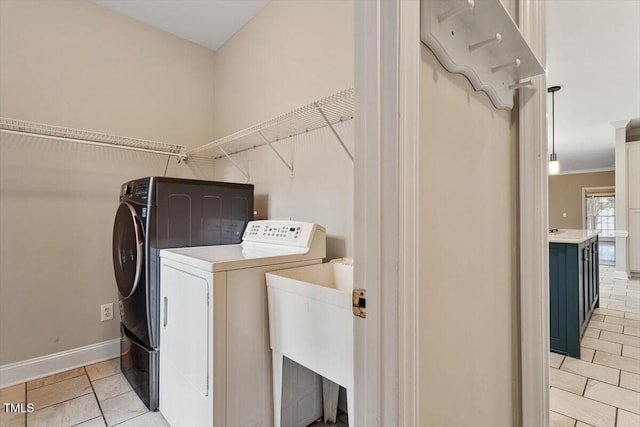 clothes washing area featuring crown molding, sink, washer and dryer, and light tile patterned floors