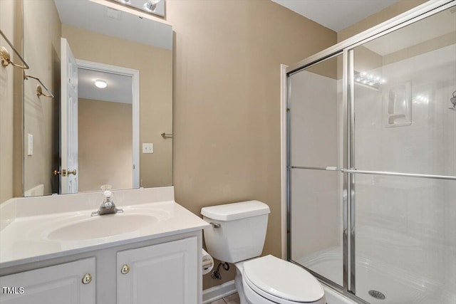 bathroom featuring vanity, toilet, and a shower with shower door