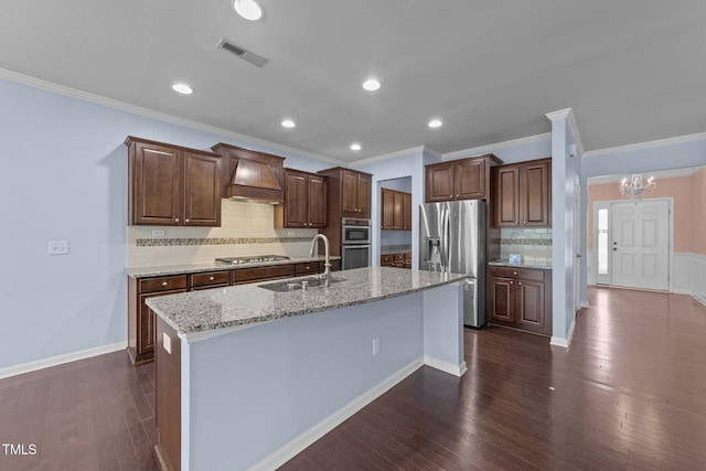 kitchen featuring sink, dark wood-type flooring, stainless steel appliances, an island with sink, and wall chimney exhaust hood