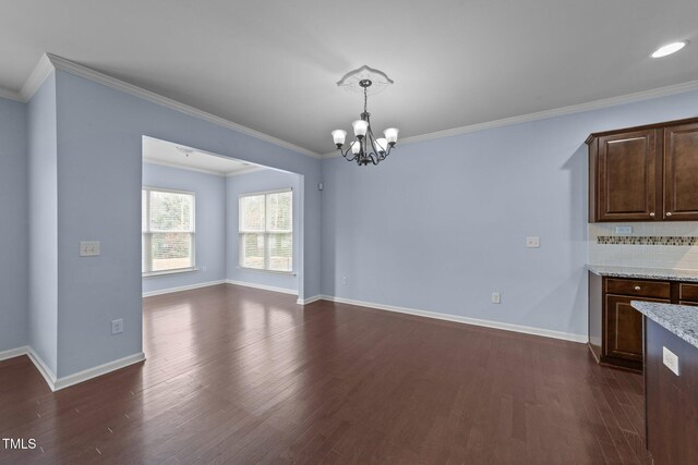 unfurnished dining area with crown molding, dark hardwood / wood-style floors, and a chandelier