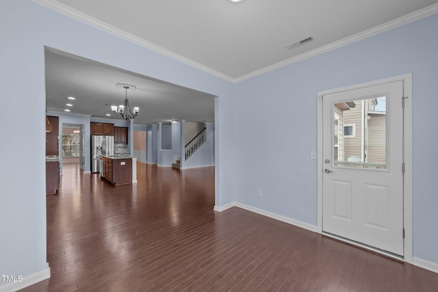 foyer with dark wood-type flooring, ornamental molding, and a chandelier