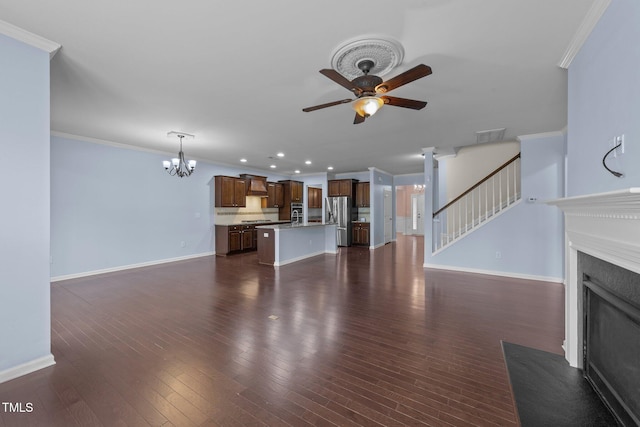 unfurnished living room featuring crown molding, ceiling fan with notable chandelier, and dark hardwood / wood-style flooring