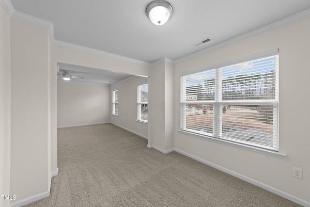 spare room featuring light colored carpet, ornamental molding, and plenty of natural light