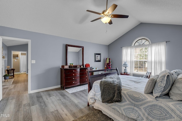 bedroom with lofted ceiling, a textured ceiling, wood finished floors, a ceiling fan, and baseboards