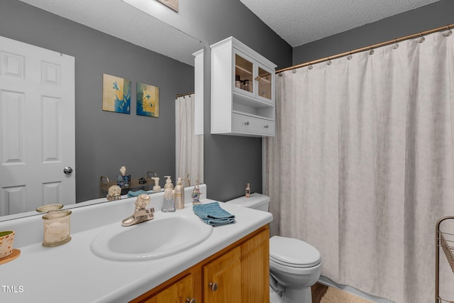 full bathroom with toilet, a textured ceiling, and vanity