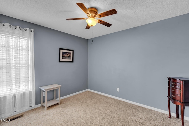 carpeted spare room with a textured ceiling, baseboards, visible vents, and a healthy amount of sunlight