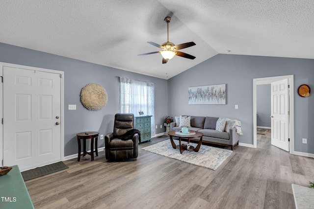 living room featuring baseboards, ceiling fan, wood finished floors, vaulted ceiling, and a textured ceiling