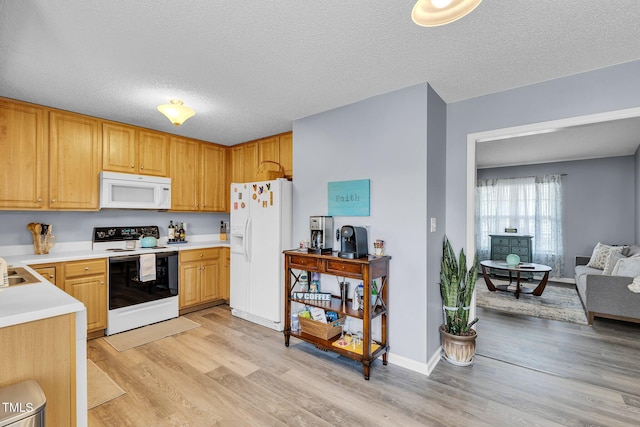 kitchen featuring a textured ceiling, light countertops, white appliances, and light wood-style flooring