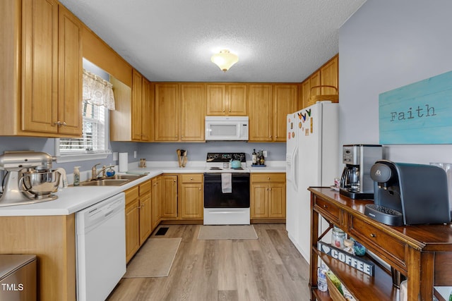 kitchen with white appliances, light countertops, a textured ceiling, light wood-type flooring, and a sink