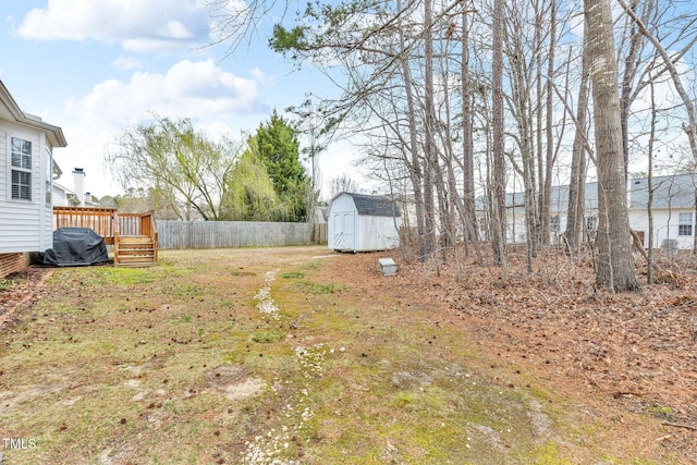 view of yard featuring an outbuilding, fence, a deck, and a storage unit