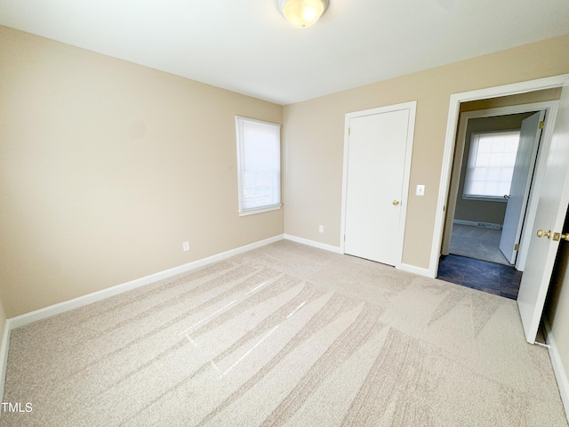 unfurnished bedroom featuring multiple windows and light colored carpet