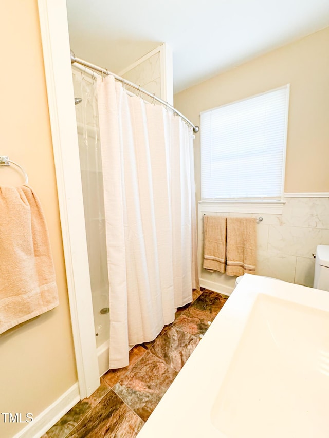 bathroom featuring a shower with shower curtain and tile walls