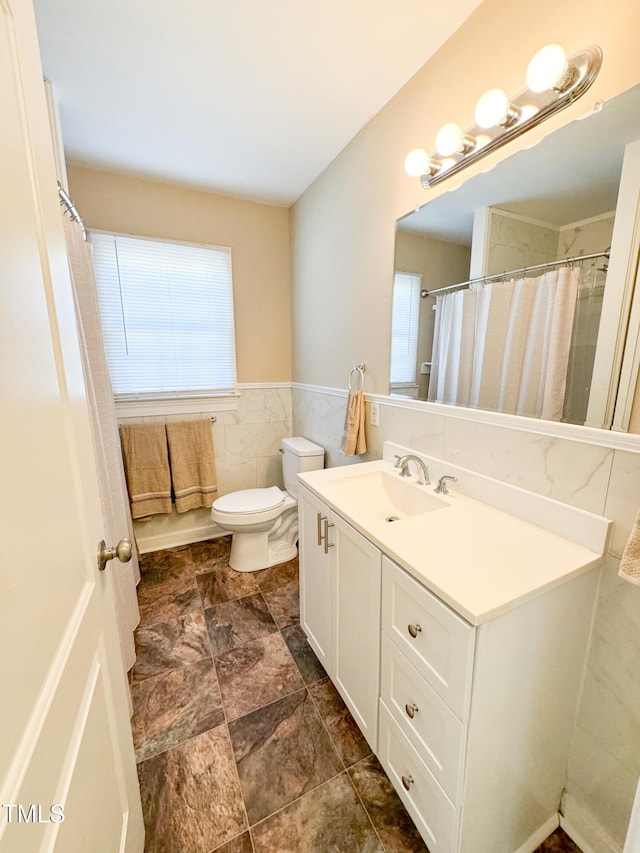 bathroom with vanity, toilet, and tile walls