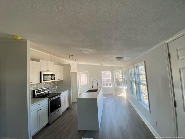 kitchen featuring sink, appliances with stainless steel finishes, backsplash, white cabinets, and a kitchen island