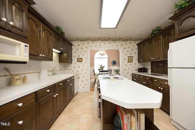 kitchen featuring dark brown cabinetry, sink, a notable chandelier, and white appliances