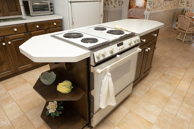 kitchen featuring electric stove, dark brown cabinetry, a center island, and white fridge