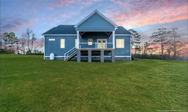 back house at dusk with a lawn