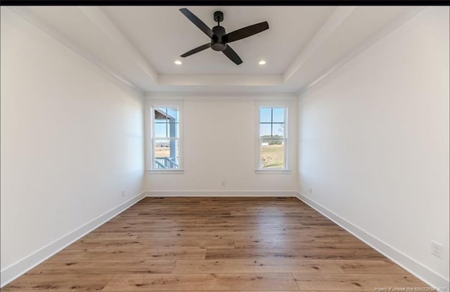 spare room featuring a tray ceiling, light hardwood / wood-style floors, and ceiling fan