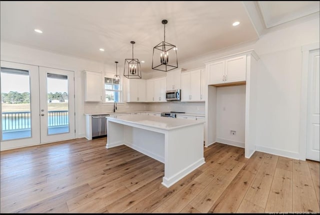 kitchen featuring pendant lighting, white cabinetry, a center island, light hardwood / wood-style floors, and stainless steel appliances