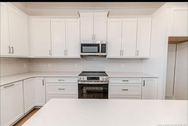 kitchen featuring stainless steel appliances, white cabinetry, and backsplash