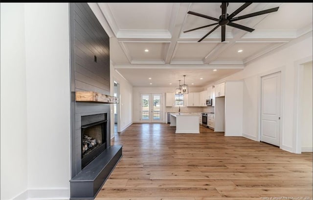 unfurnished living room featuring beam ceiling, coffered ceiling, a large fireplace, and light hardwood / wood-style floors