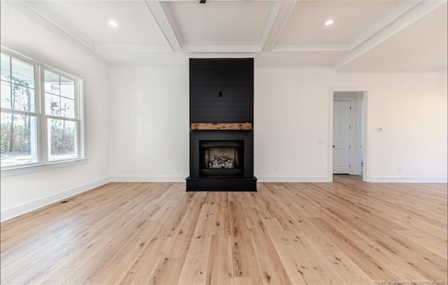 unfurnished living room with coffered ceiling, a large fireplace, beamed ceiling, and light wood-type flooring