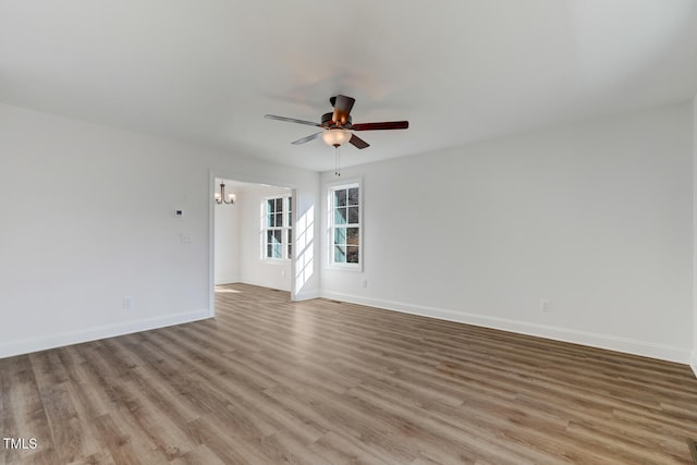 unfurnished room with ceiling fan with notable chandelier and light hardwood / wood-style flooring