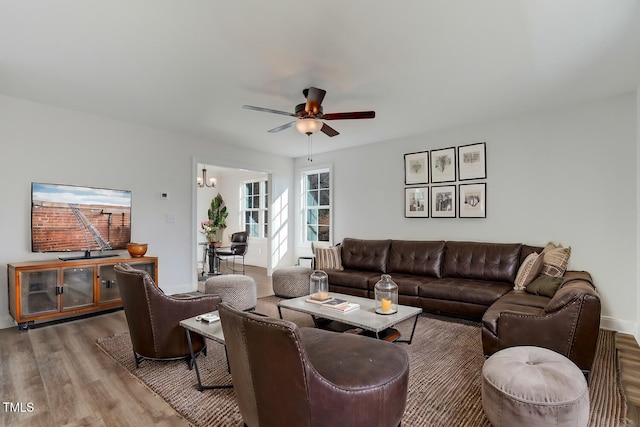 living room with wood-type flooring and ceiling fan with notable chandelier