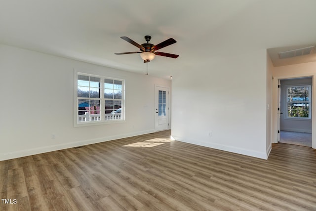 empty room featuring ceiling fan, light wood-type flooring, and a wealth of natural light