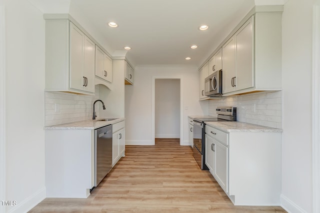 kitchen with white cabinetry, appliances with stainless steel finishes, sink, and light hardwood / wood-style flooring