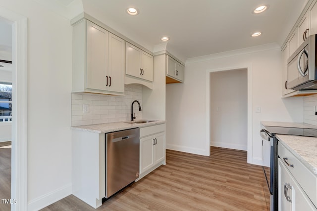 kitchen featuring appliances with stainless steel finishes, sink, decorative backsplash, light stone counters, and light hardwood / wood-style flooring