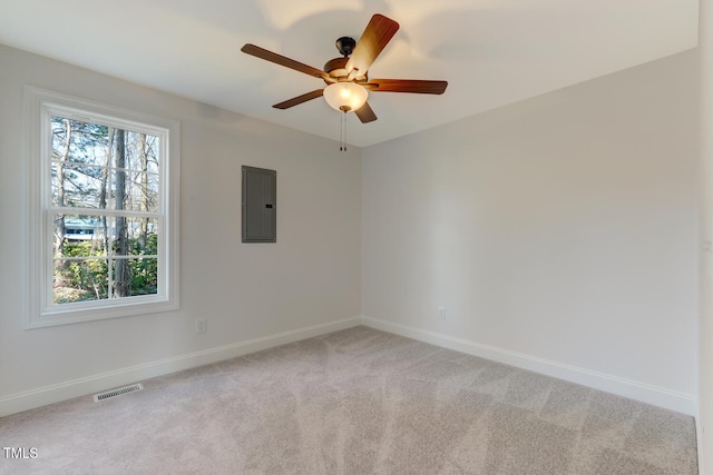 spare room with ceiling fan, light colored carpet, and electric panel