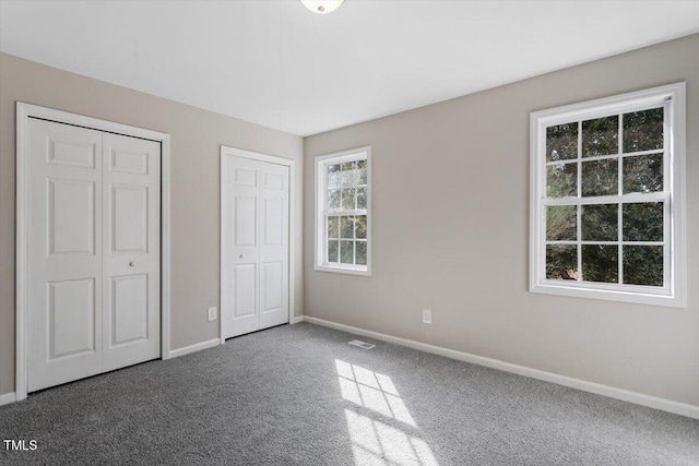 unfurnished bedroom with multiple closets and carpet