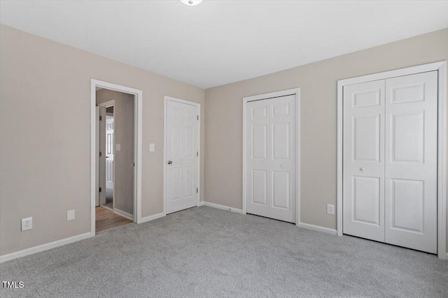 unfurnished bedroom featuring two closets and light colored carpet