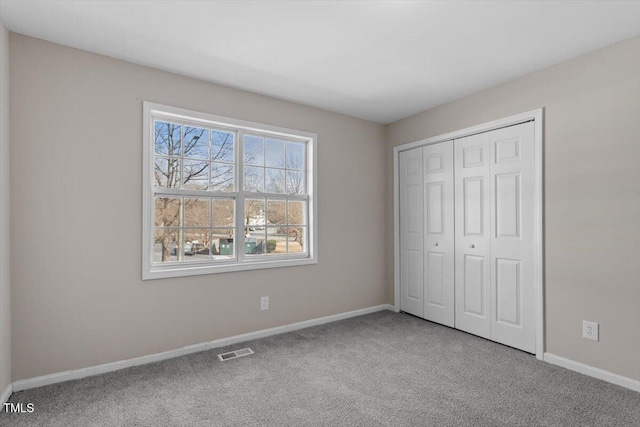 unfurnished bedroom with light carpet and a closet