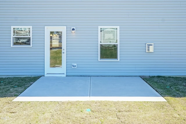 view of exterior entry featuring a yard and a patio