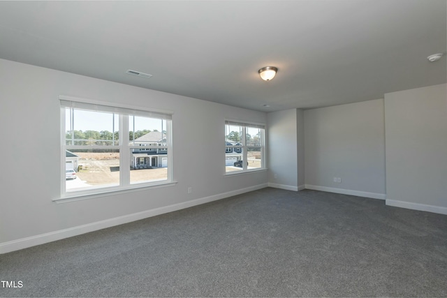 spare room with dark carpet and a wealth of natural light