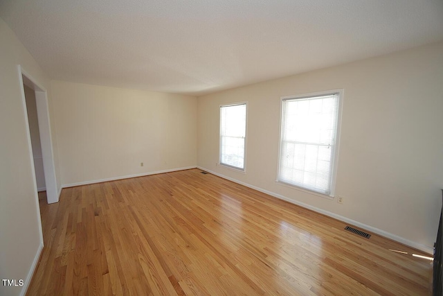 unfurnished room with light wood-style floors, baseboards, and visible vents