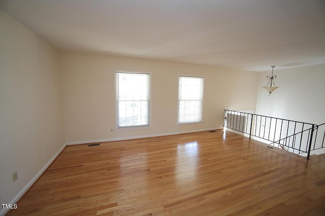 unfurnished room featuring light wood-type flooring, visible vents, and baseboards