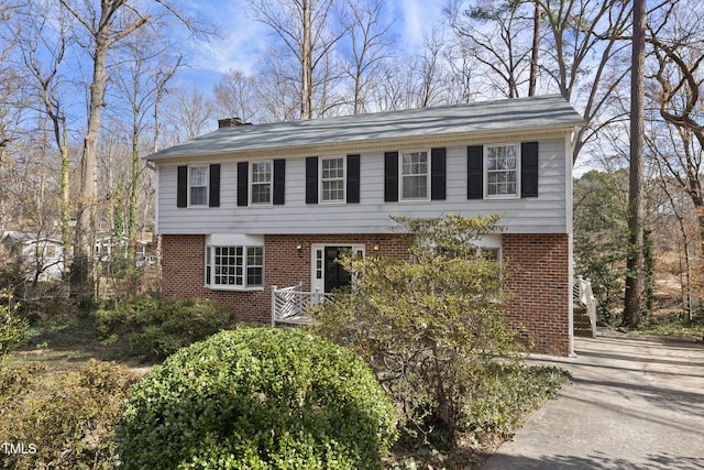 colonial-style house featuring brick siding and a chimney