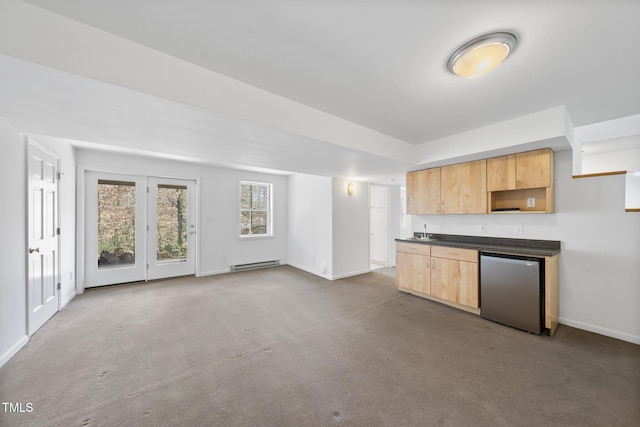 kitchen with dark countertops, refrigerator, carpet, baseboard heating, and light brown cabinetry