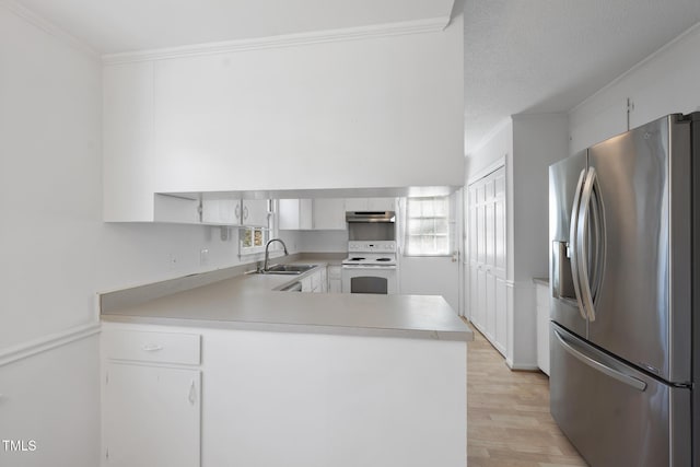 kitchen with electric stove, crown molding, a sink, stainless steel fridge, and a peninsula