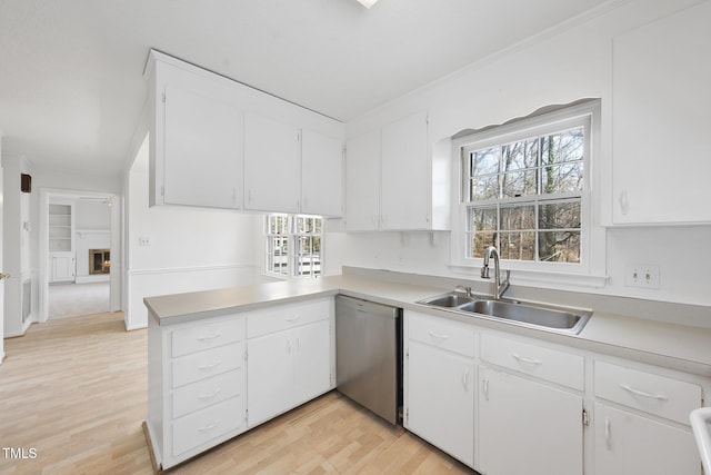 kitchen with a sink, crown molding, light countertops, and stainless steel dishwasher