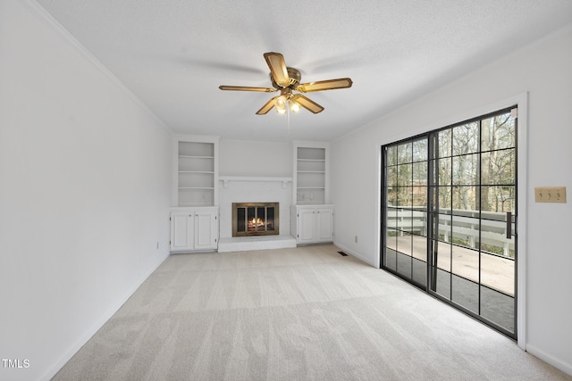 unfurnished living room featuring a ceiling fan, a glass covered fireplace, light colored carpet, and a textured ceiling