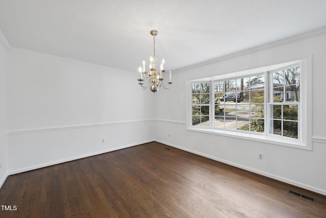 spare room featuring crown molding, visible vents, an inviting chandelier, wood finished floors, and baseboards