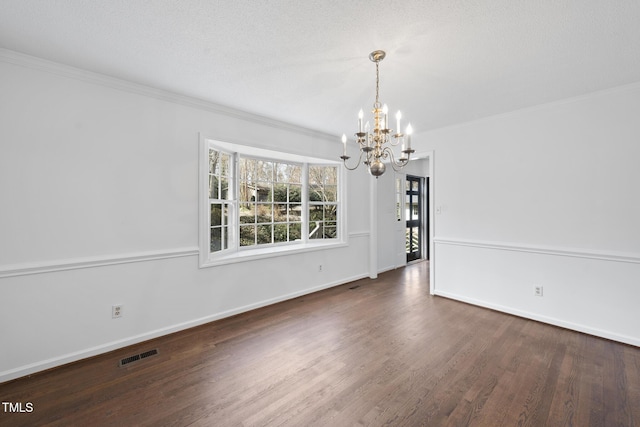 unfurnished dining area featuring baseboards, visible vents, ornamental molding, wood finished floors, and a chandelier