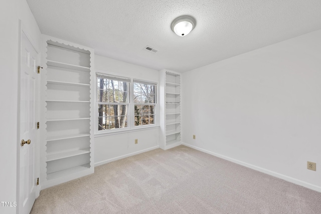 spare room featuring carpet floors, visible vents, baseboards, and a textured ceiling