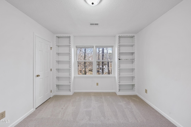 unfurnished bedroom featuring baseboards, visible vents, a textured ceiling, and carpet flooring