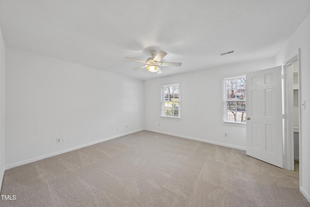 empty room featuring carpet, visible vents, ceiling fan, and a textured ceiling